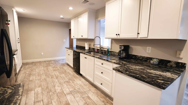 kitchen featuring dishwasher, sink, light hardwood / wood-style floors, dark stone counters, and white cabinets