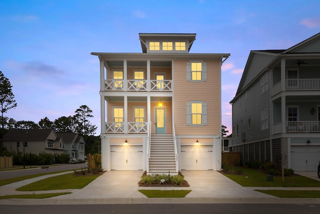 raised beach house featuring an attached garage, stairway, and concrete driveway