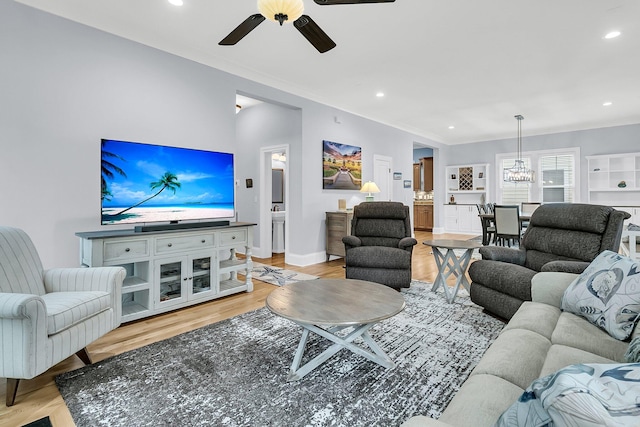 living room featuring ceiling fan with notable chandelier and light wood-type flooring