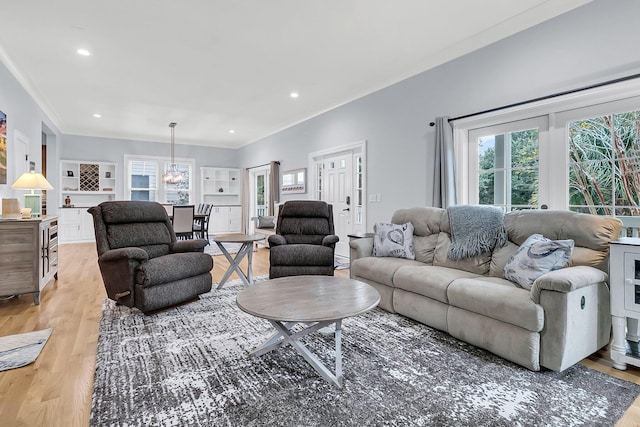 living room featuring light hardwood / wood-style flooring, a notable chandelier, and ornamental molding