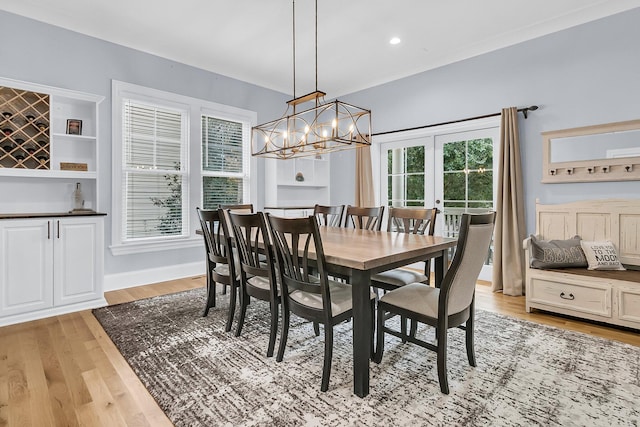 dining space featuring french doors, light wood-type flooring, a wealth of natural light, and a notable chandelier