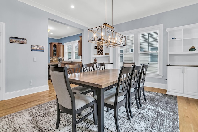 dining room featuring wood-type flooring, a wealth of natural light, ornamental molding, and a notable chandelier