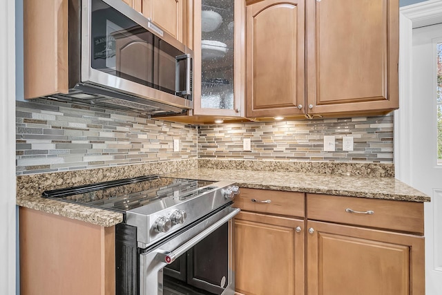 kitchen featuring tasteful backsplash, light stone counters, and appliances with stainless steel finishes