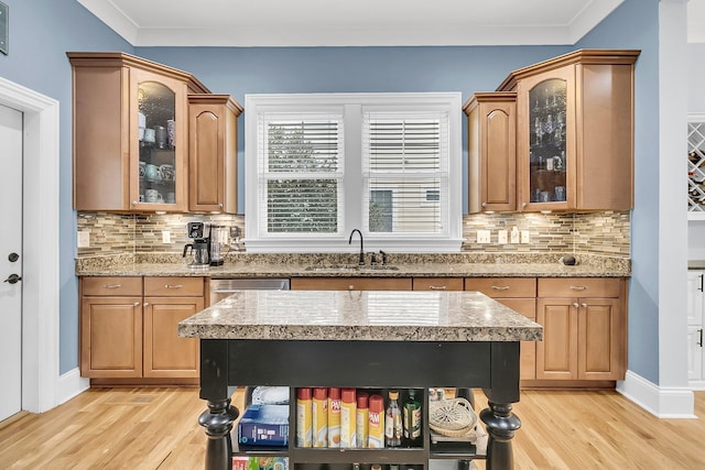 kitchen with backsplash, ornamental molding, sink, and light hardwood / wood-style flooring