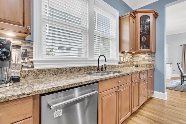 kitchen featuring dishwasher, sink, tasteful backsplash, light stone counters, and light hardwood / wood-style floors