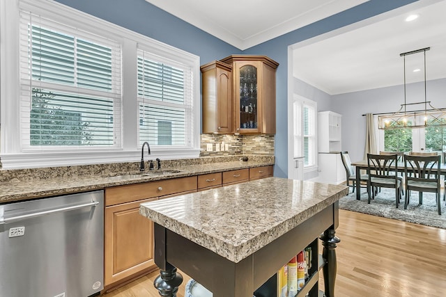 kitchen with pendant lighting, crown molding, sink, light hardwood / wood-style flooring, and stainless steel dishwasher