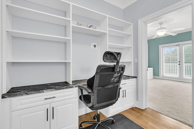 home office featuring ceiling fan, built in desk, and light hardwood / wood-style floors