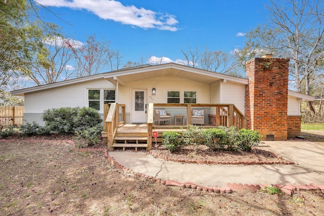 view of front of house featuring a chimney, a deck, and fence