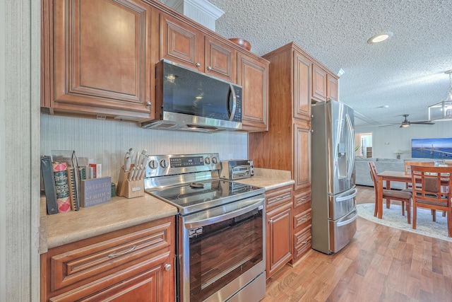 kitchen featuring ceiling fan, light wood-type flooring, appliances with stainless steel finishes, and a textured ceiling