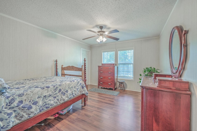 bedroom featuring ceiling fan, a textured ceiling, ornamental molding, and hardwood / wood-style flooring