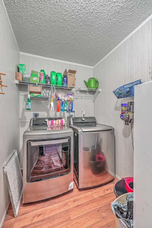 laundry room with washing machine and dryer, crown molding, and hardwood / wood-style floors