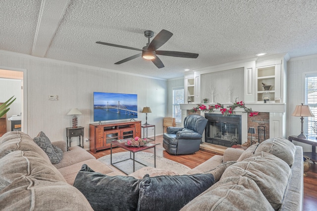 living room featuring ceiling fan, ornamental molding, a textured ceiling, and hardwood / wood-style flooring