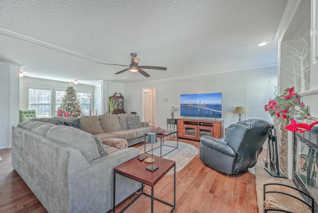 living room featuring a textured ceiling, ceiling fan, wood-type flooring, and decorative columns