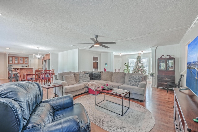 living room featuring a textured ceiling, crown molding, ceiling fan with notable chandelier, and light hardwood / wood-style flooring