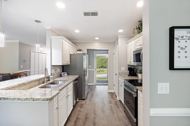 kitchen with visible vents, a sink, decorative backsplash, stainless steel appliances, and light wood-type flooring