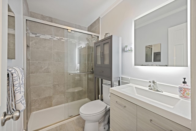 bathroom featuring vanity, wood finished floors, a stall shower, crown molding, and toilet