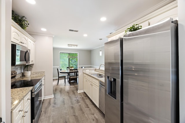 kitchen with light wood finished floors, visible vents, stainless steel appliances, and ornamental molding