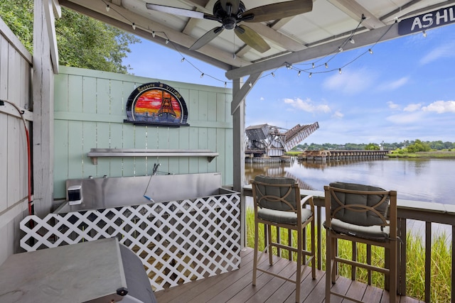 wooden deck with a ceiling fan and a water view