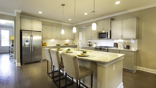 kitchen with decorative light fixtures, a center island with sink, light stone countertops, stainless steel appliances, and dark hardwood / wood-style flooring