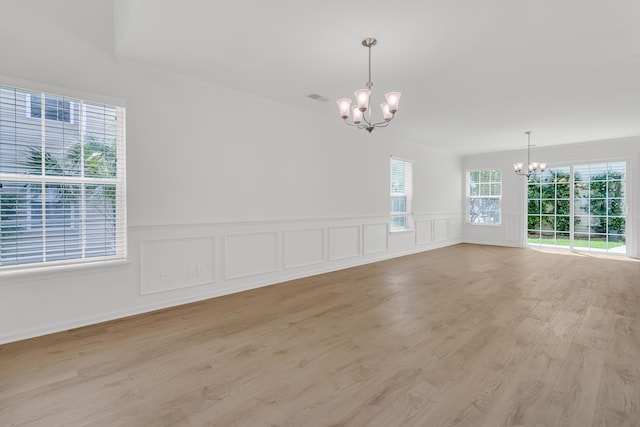 4823 Shady Tree Ln, Summerville, SC 29485 - empty room featuring a chandelier, light wood finished floors, a wainscoted wall, and a decorative wall