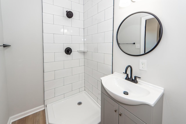 bathroom with hardwood / wood-style flooring, vanity, and a tile shower