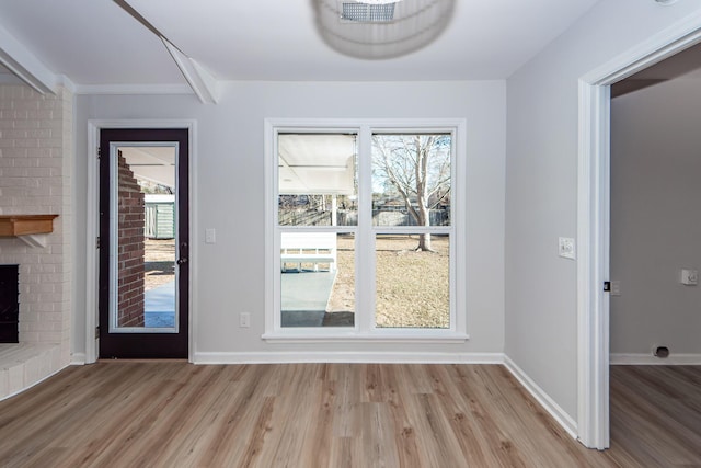 entryway with light hardwood / wood-style floors and a brick fireplace