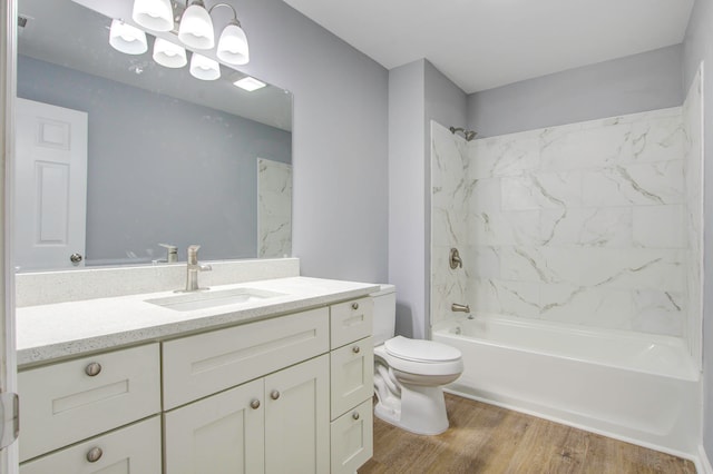 full bathroom with toilet, tiled shower / bath, wood-type flooring, vanity, and a chandelier