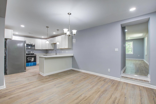 kitchen featuring kitchen peninsula, appliances with stainless steel finishes, light hardwood / wood-style flooring, hanging light fixtures, and white cabinets