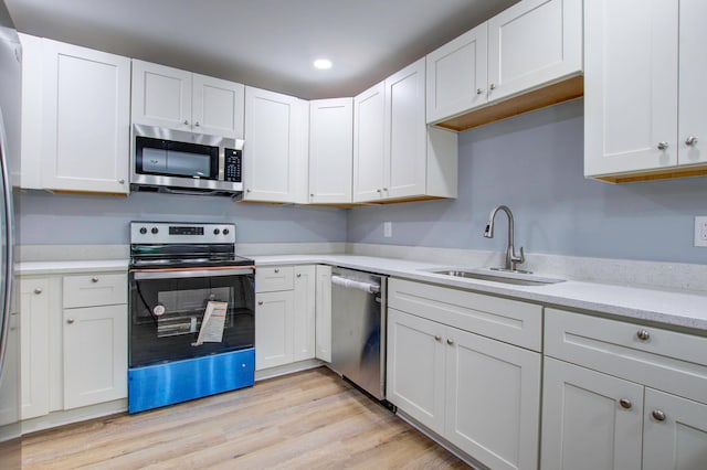 kitchen with light hardwood / wood-style floors, stainless steel appliances, and white cabinetry