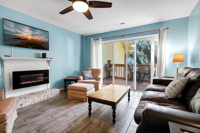 living room featuring ceiling fan, hardwood / wood-style flooring, and a textured ceiling