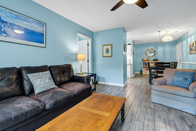 living room with wood-type flooring and ceiling fan with notable chandelier