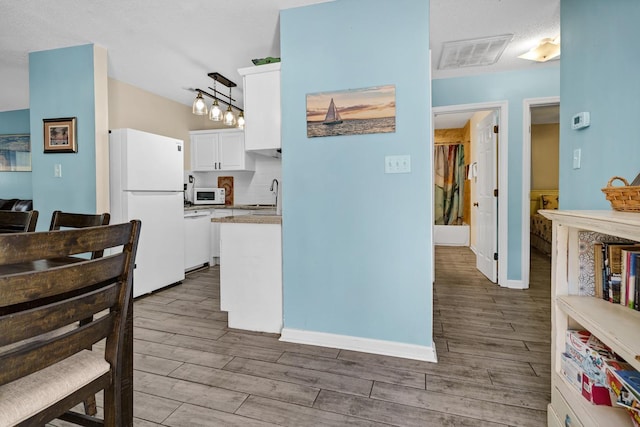 kitchen featuring white cabinetry, white appliances, decorative light fixtures, and dark hardwood / wood-style floors