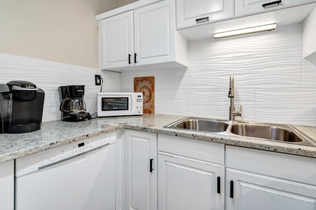 kitchen featuring dishwasher, backsplash, sink, and white cabinetry