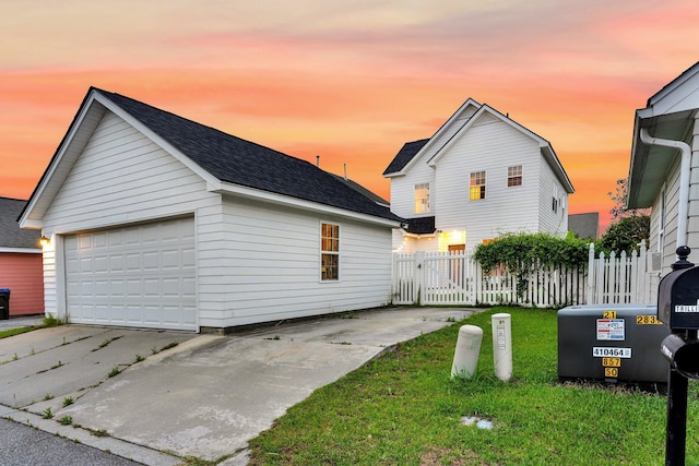 traditional-style home with fence, a garage, a shingled roof, and an outdoor structure