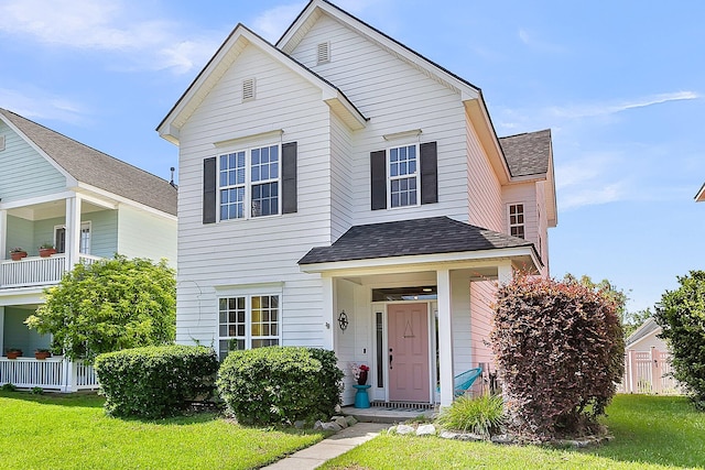 traditional-style house with a shingled roof and a front yard