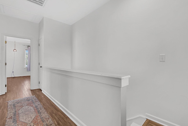 hall with wood finished floors, baseboards, and an upstairs landing