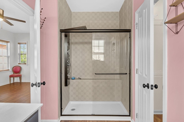 bathroom with a stall shower, ceiling fan, vanity, wood finished floors, and baseboards