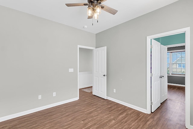 unfurnished bedroom with wood finished floors, baseboards, and a ceiling fan