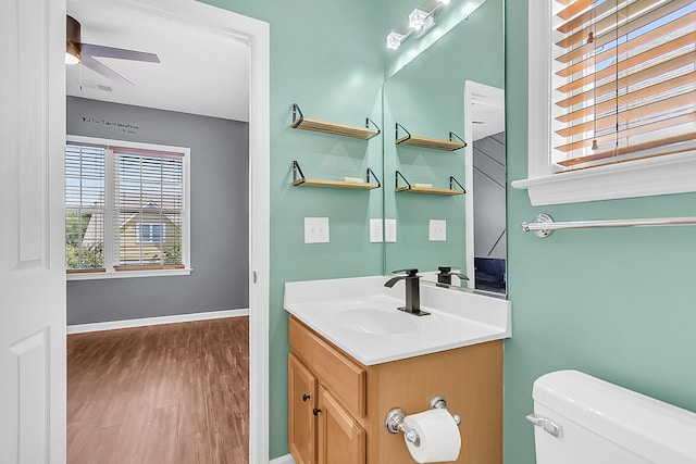 bathroom with wood finished floors, toilet, ceiling fan, vanity, and baseboards