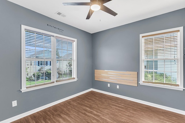 empty room featuring healthy amount of natural light, baseboards, dark wood-type flooring, and ceiling fan