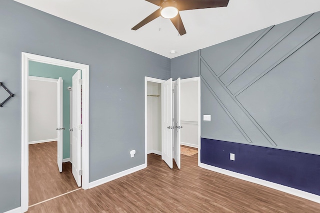 unfurnished bedroom featuring wood finished floors, baseboards, a closet, and ceiling fan