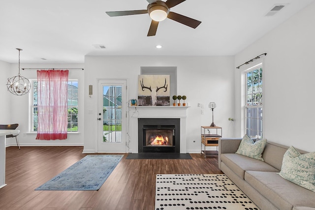 living room with wood finished floors, a lit fireplace, a chandelier, a ceiling fan, and recessed lighting