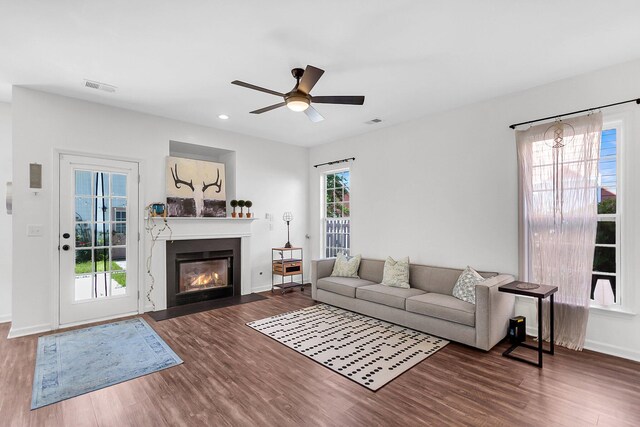 living area with wood finished floors, a ceiling fan, a fireplace with flush hearth, baseboards, and recessed lighting