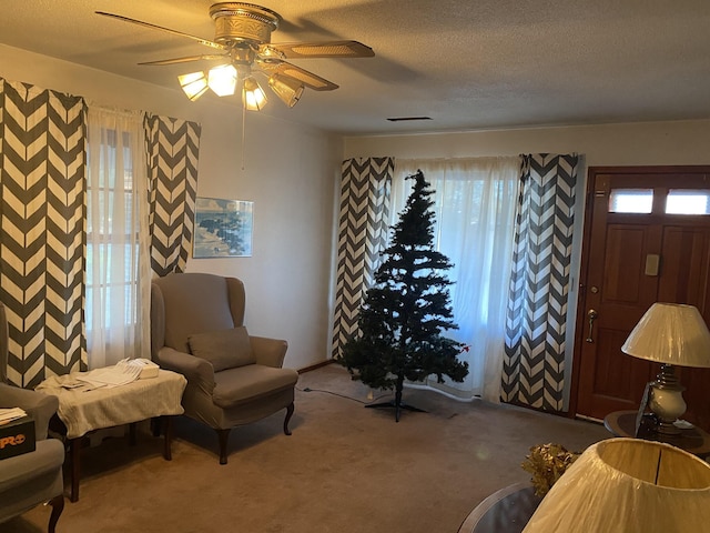 living area featuring carpet flooring, a wealth of natural light, ceiling fan, and a textured ceiling