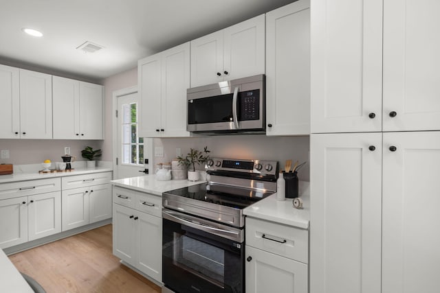 kitchen with appliances with stainless steel finishes, light countertops, white cabinets, and recessed lighting