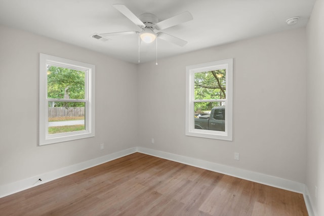 spare room featuring plenty of natural light, a smoke detector, light wood-style floors, and baseboards