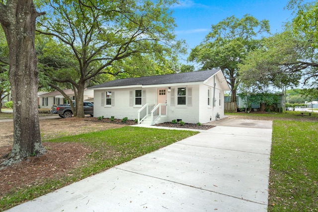 bungalow-style home with driveway, brick siding, and a front yard