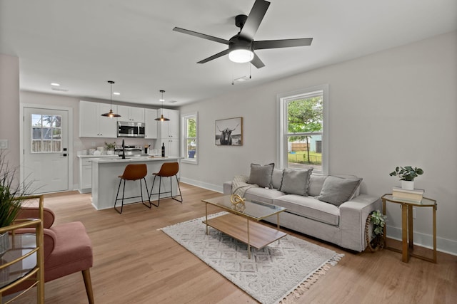living room featuring baseboards, light wood-style flooring, recessed lighting, and ceiling fan
