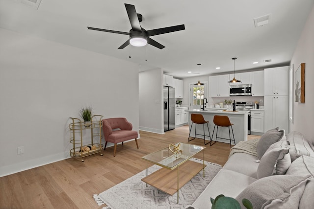 living area with recessed lighting, ceiling fan, light wood-style floors, and baseboards