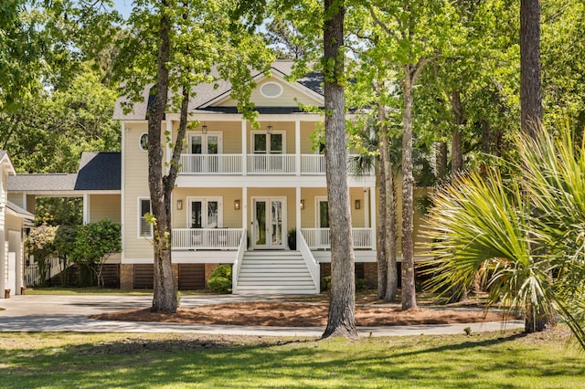 greek revival inspired property with covered porch, french doors, stairway, a balcony, and driveway